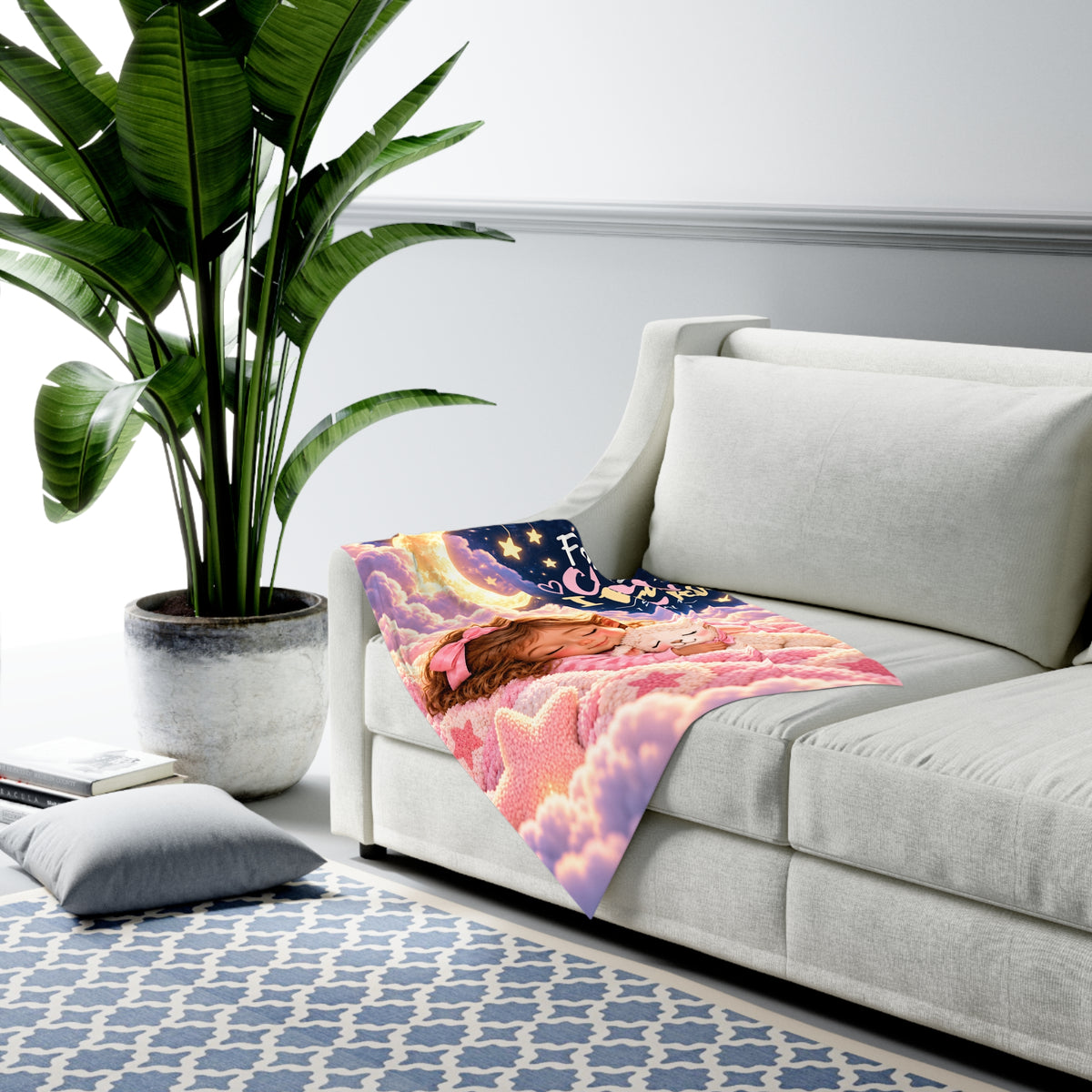 Pink Christian baby swaddle blanket with moon and lamb design draped on a sofa
