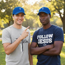 Two men wearing blue caps and casual clothing outdoors with a blurred natural background